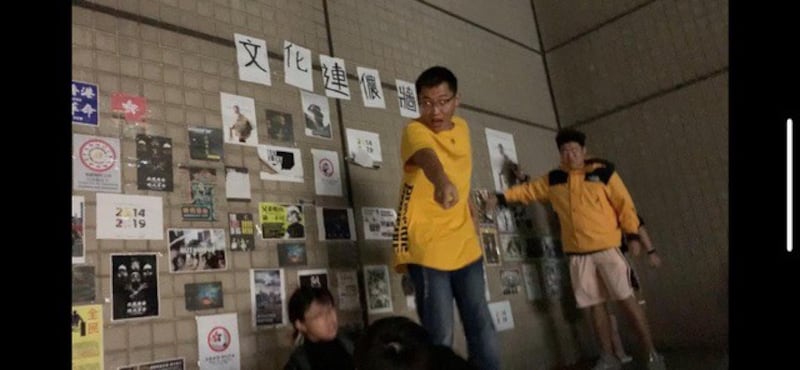 台湾的中国文化大学爆发港生贴连侬墙遭陆生撕毁、施暴。受害港生(下方)被台下女陆生拉下高台。(受害女港生提供)