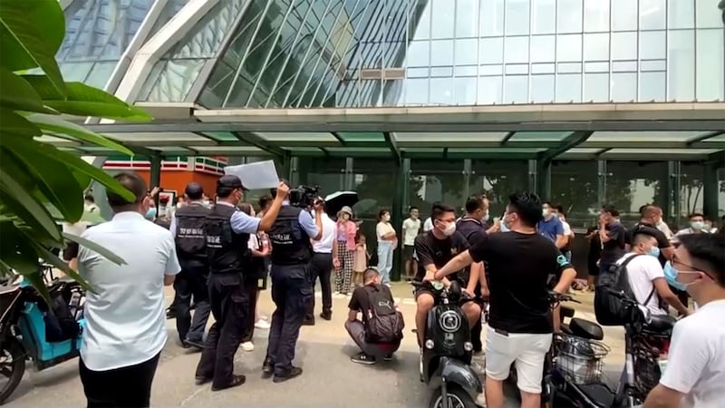 2021年9月15日,抗议者站在深圳恒大总部的入口附近,数十名安保人员阻止他们进入。(路透社视频截图)